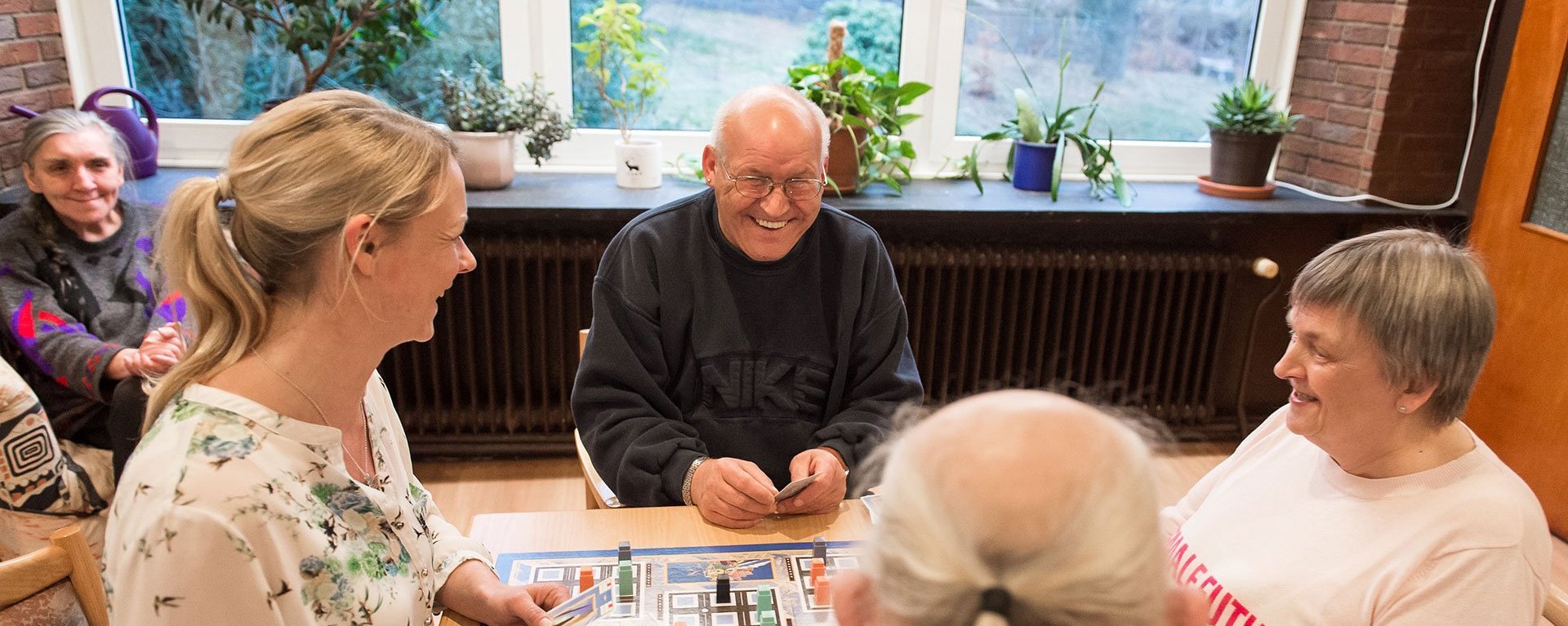 Aufenthaltsraum: zwei Frauen und zwei Männer spielen ein Brettspiel