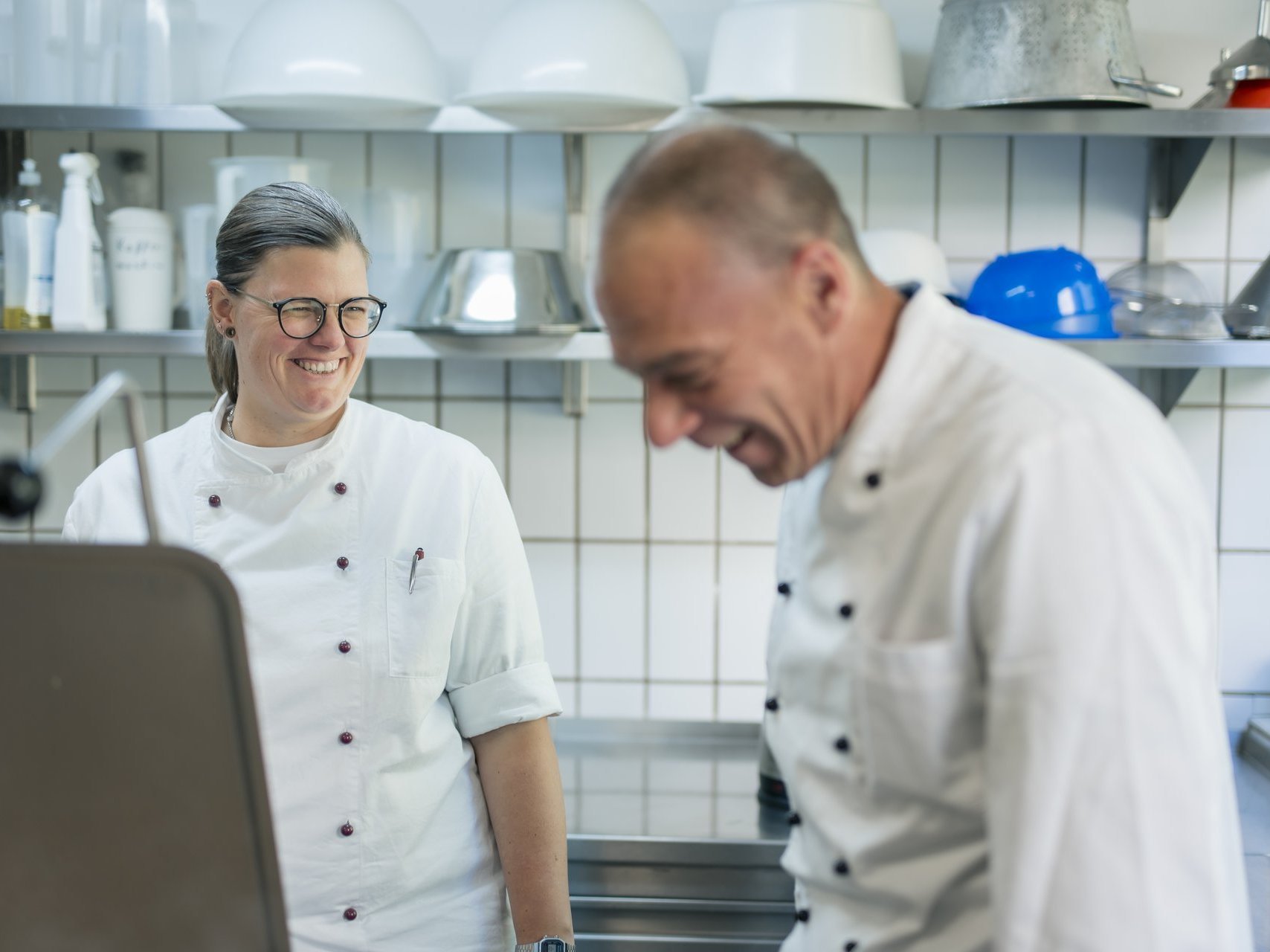 Eine Frau und ein Mann unterhalten sich, während sie in der Küche arbeiten.