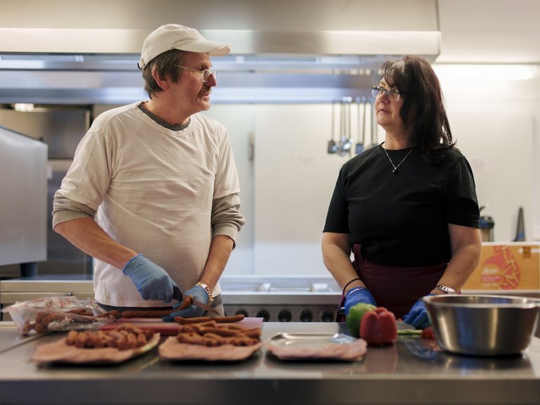 Ein Mann und eine Frau stehen in der Küche und bereiten Würste vor.