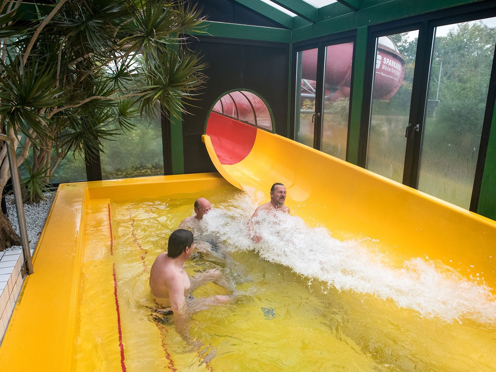 Drei Männer beim Wasserrutschen im Schwimmbad 